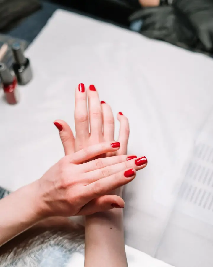 Mani con smalto rosso durante una manicure