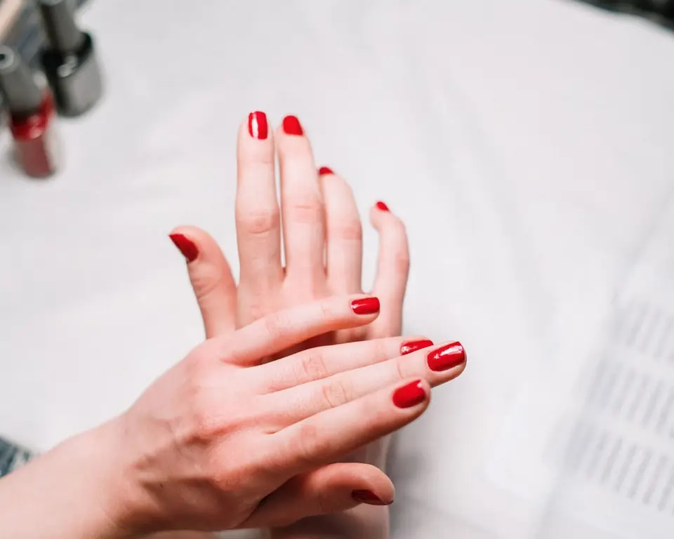 Mani con smalto rosso durante una manicure
